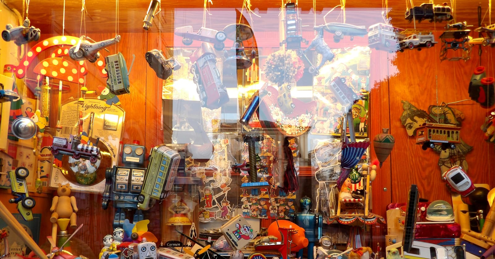 Vitrine de loja de brinquedos cheia de itens coloridos pendurados, ilustrando o movimento do comércio no Dia das Crianças