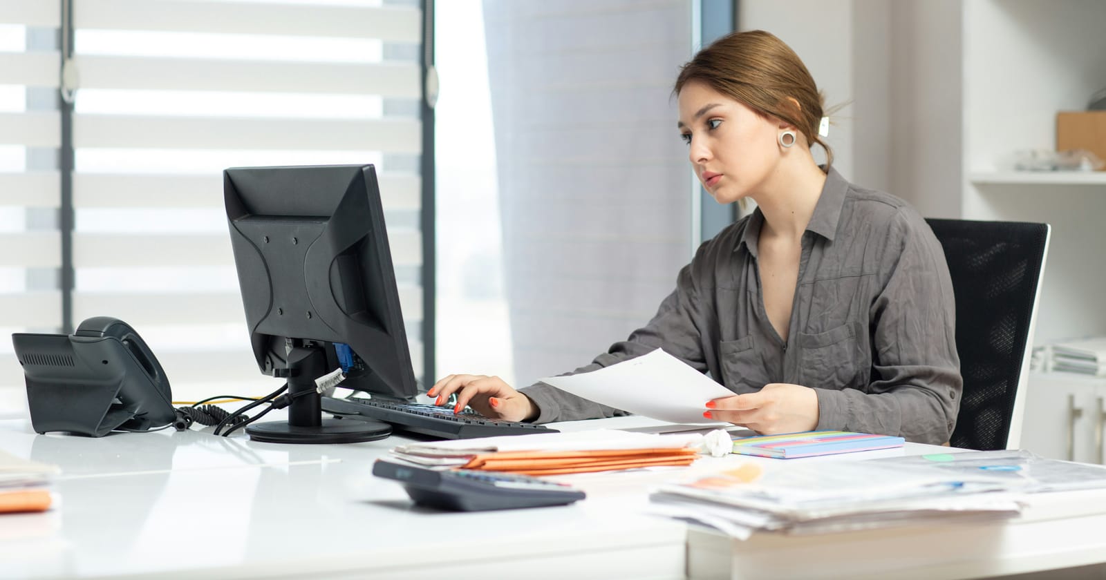 Profissional revisando pilhas de papel na mesa do escritório, tentando organizar vendas sem um crm