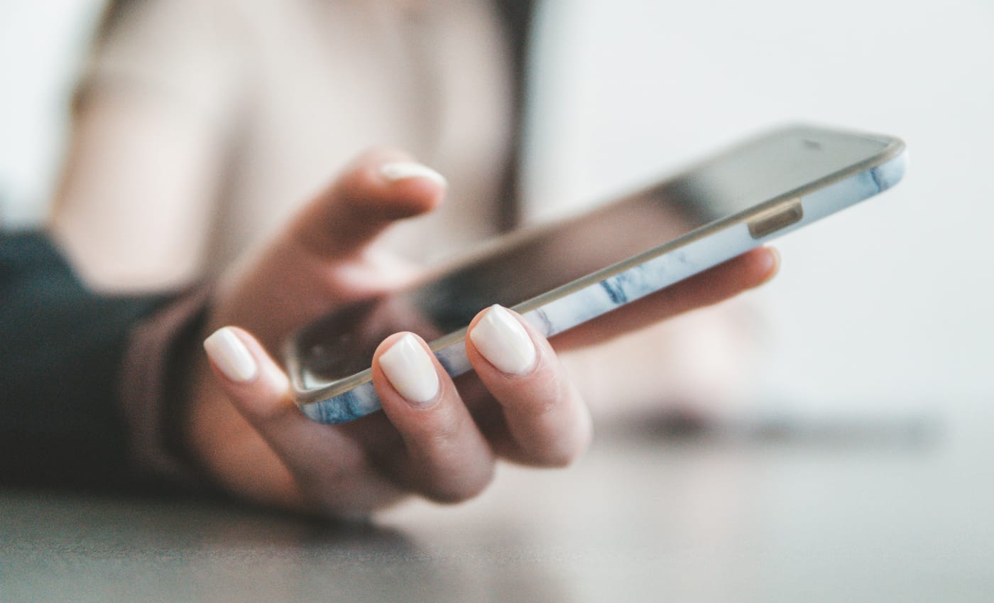 Mão segurando um celular para enviar uma mensagem agendada a um cliente