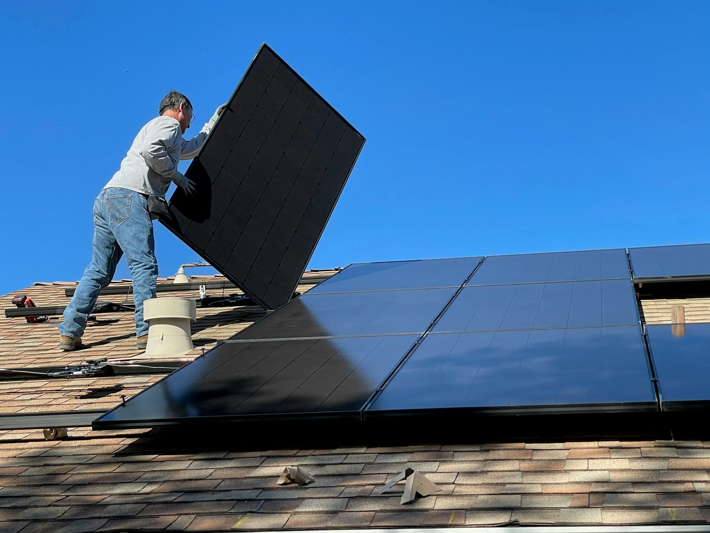 Instalador colocando placa solar sobre um telhado residencial em dia de sol