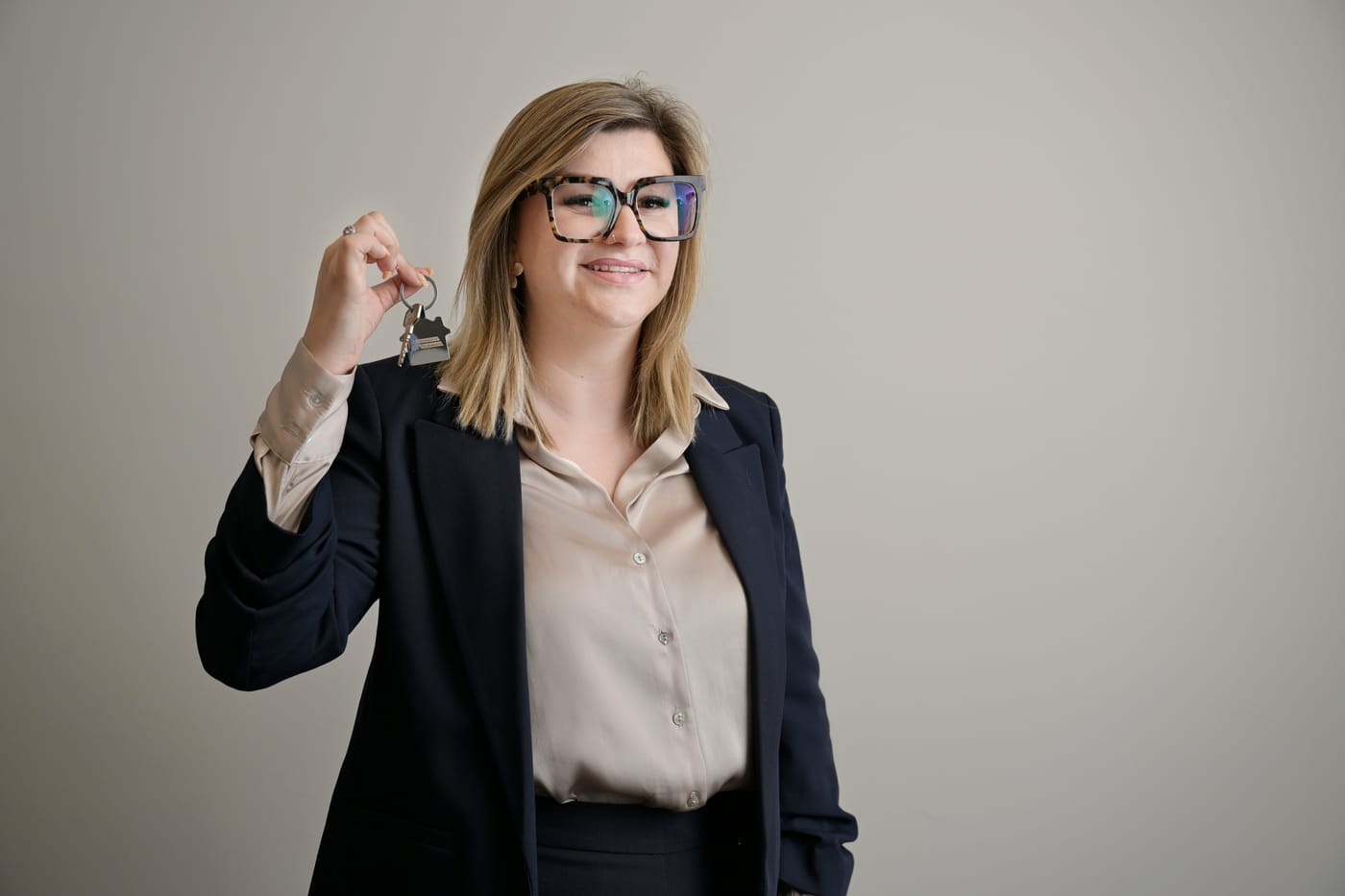 Corretora de imóveis sorridente segurando chaveiro em formato de casa