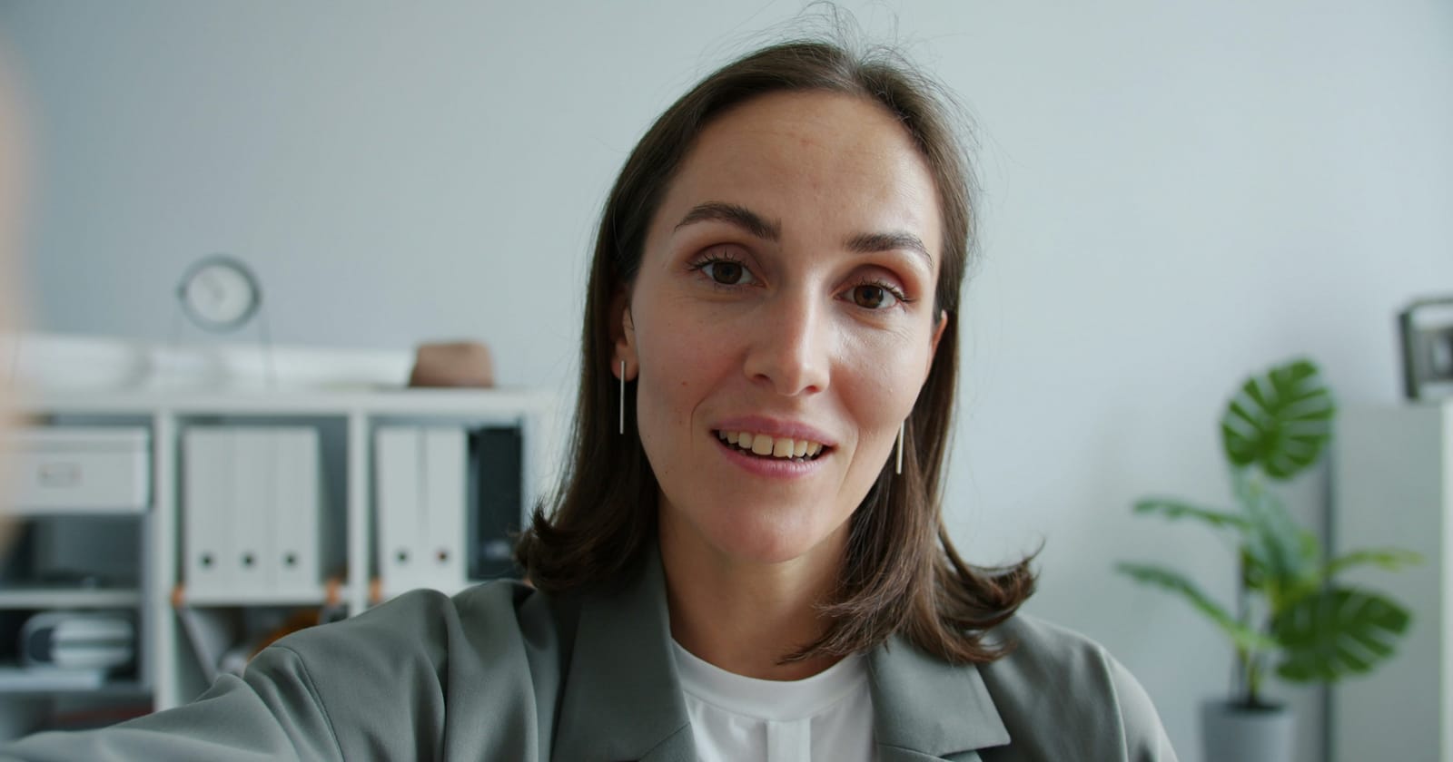 Empresária sorrindo durante uma videochamada pelo celular, representando o atendimento comercial por vídeo